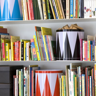 Bookshelves with colorful books and JR–Work–Shop's Acne Jr Toy Brand drum-inspired containers