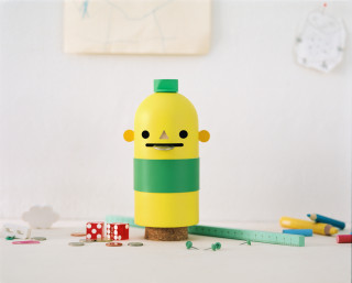 Acne Jr Toy by JR–Work–Shop, yellow and green wooden toy with a simplistic face