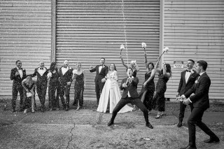 Wedding party celebrating by spraying champagne, by Todd and Alyda McGaw