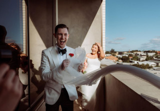 Groom laughing with billowing veil on balcony by Todd and Alyda McGaw