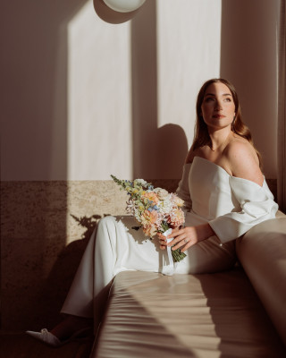 Woman in off-shoulder white outfit holding pastel bouquet, by Todd and Alyda McGaw