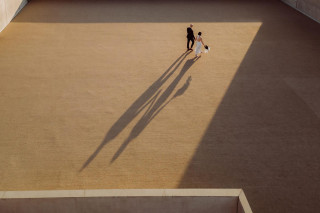 Bride and groom holding hands with long shadows on a vast plain surface