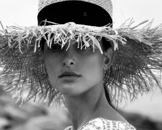 Black and white photo by Vivienne Balla of a person wearing a wide-brimmed straw hat with a patterned dress