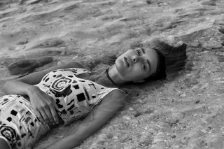 Vivienne Balla photograph of a woman lying in shallow water wearing patterned attire